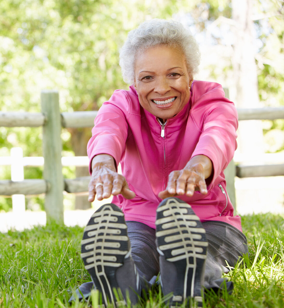 Active senior, stretching while seated in the grass/